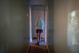 A photo of an elderly woman walking down a hallway indoors.