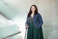 A portrait of a young woman leaning gently on a cane.