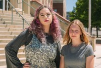 Two teenage girls pose in front of a courthouse.