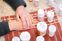 Sheldon Ekirch with her hands folded on a table next to her pill bottles.