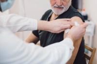 A photo of an older man having his arm bandaged after getting a vaccine.