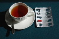 A photo of a cup of tea with a blister pack of iron pills next to it.