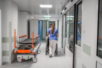 A photo of a nurse pushing a patient in a wheelchair in a hospital corridor.