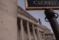A photo of the U.S. Capitol. In the foreground is part of a sign that reads, "closed."
