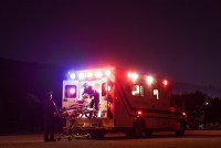 A photo of an ambulance. Paramedics load a patient on a gurney into the ambulance.