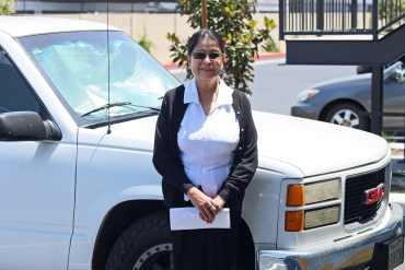 A photo of a woman standing outside by a truck.