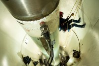 A photo of a firefighter repelling on cords inside of a missile silo.