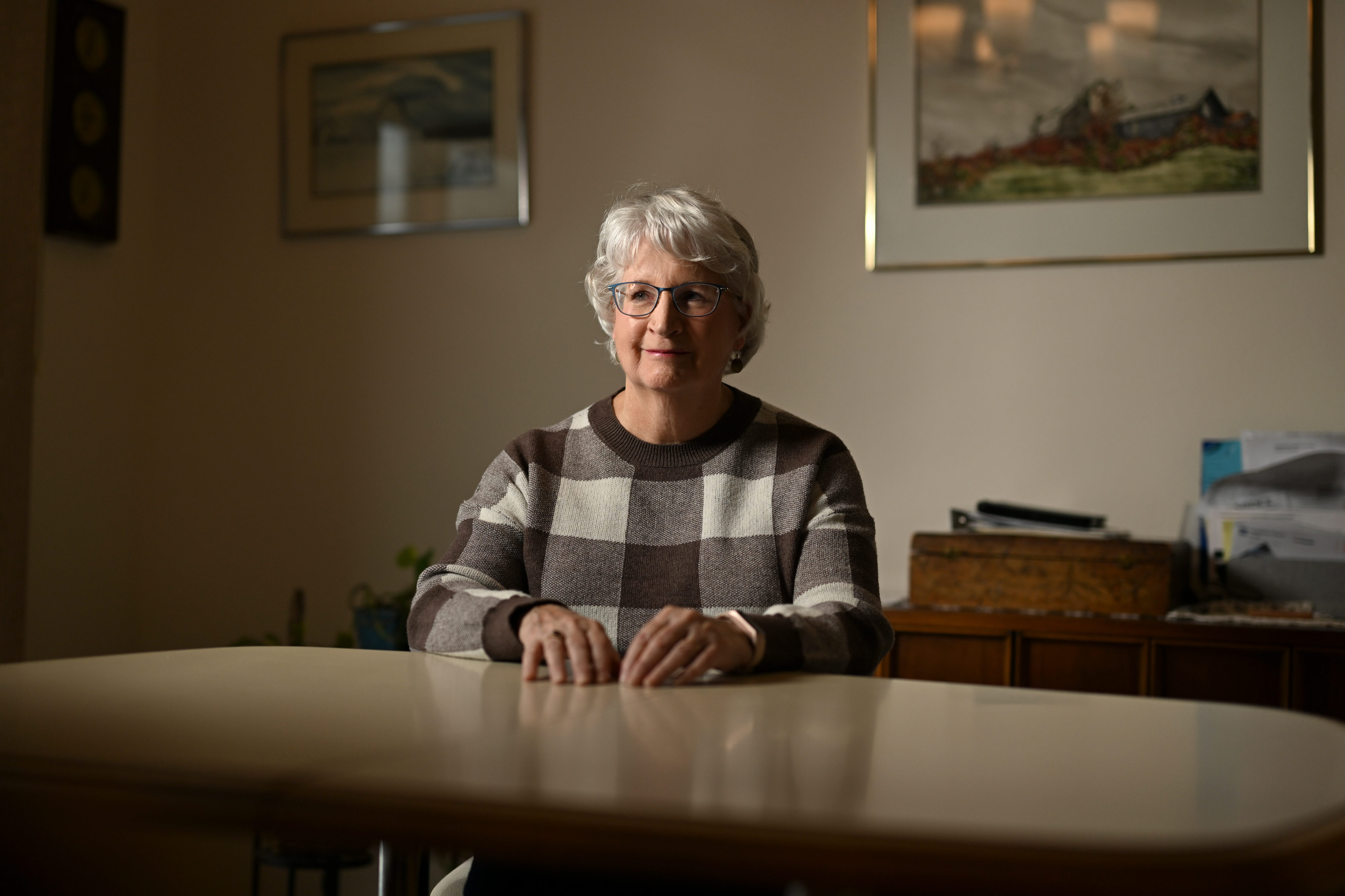 Barbara Tuszynski sits at a table in her home.