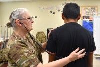 A photo of a Texas State Guard member checking a patient with a stethoscope.