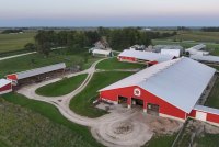 An aerial view of a farm with a red barn and several buildings around it.