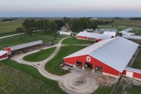 An aerial view of a farm with a red barn and several buildings around it.
